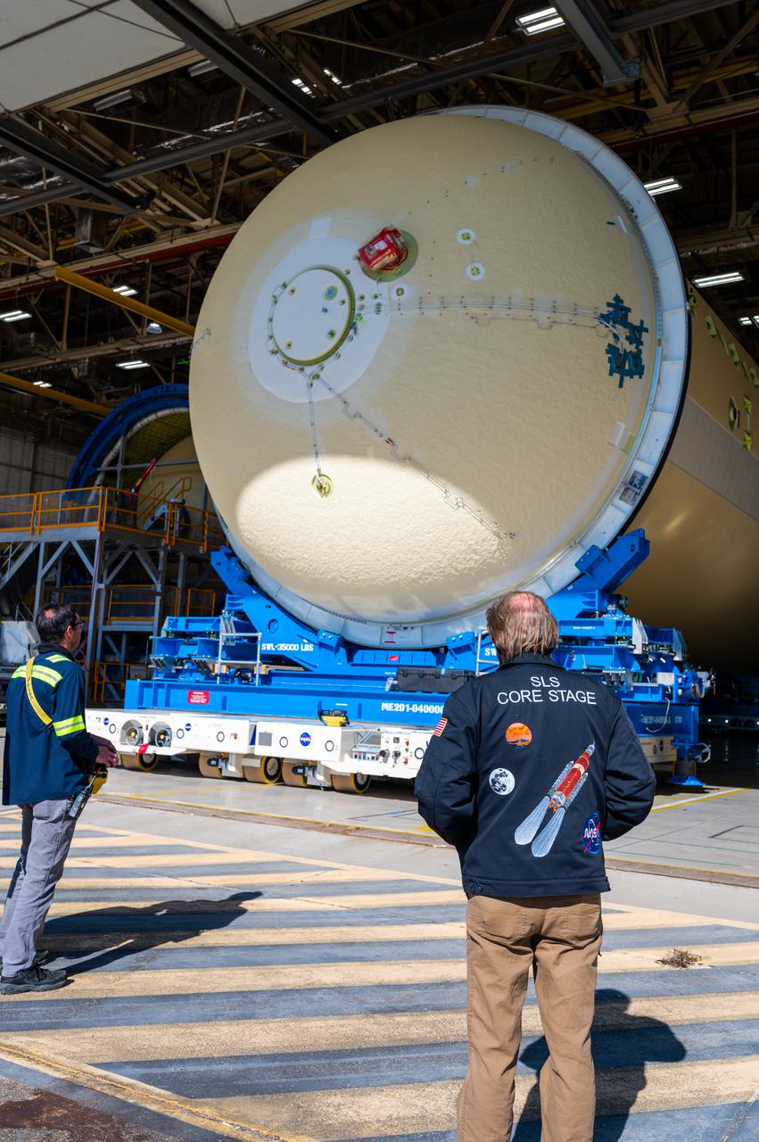 Technicians transported the assembled upper part of the Artemis II core stage to the final assembly area inside the factory at NASA’s Michoud Assembly Facility in New Orleans.  On Jan 10, the forward assembly, left was moved next to the Artemis II liquid hydrogen tank, which has been undergoing assembly. Next, Boeing, the lead core stage contractor, will join the forward assembly and the liquid hydrogen tank to complete most of the core stage for the Space Launch System (SLS) rocket that will send the first crew on an Artemis mission. The core stage consists of five major structures that are built, outfitted, and then connected to form the final stage. The forward skirt, liquid oxygen and intertank were connected and tested to form the 66-foot forward assembly. After the forward assembly is joined with the 130-foot liquid hydrogen tank, only the engine section, the fifth piece of the stage, will need to be added to complete the Artemis II core stage.  The core stage serves as the backbone of the rocket, supporting the weight of the payload, upper stage, and crew vehicle, as well as the thrust of its four RS-25 engines and two five-segment solid rocket boosters attached to the engine and intertank sections. On Artemis II, the SLS rocket will launch the Orion spacecraft and a crew, sending them into lunar orbit, in preparation for later Artemis missions that will enable the first woman and first person of color to land on the Moon.